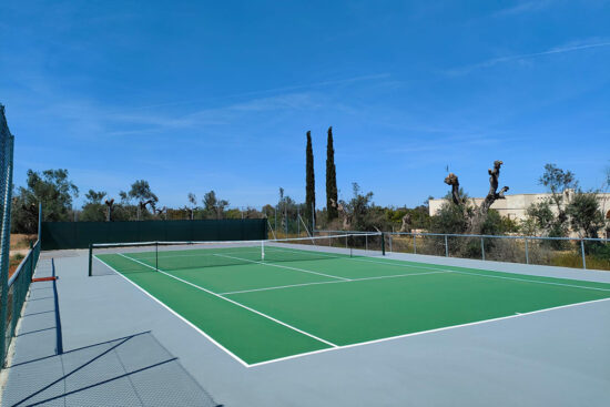 A tennis court under a bright blue sky